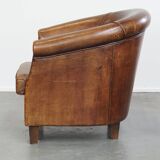 Subtle, neat sheepskin leather club armchair with a fixed seat cushion in a deep, dark cognac color