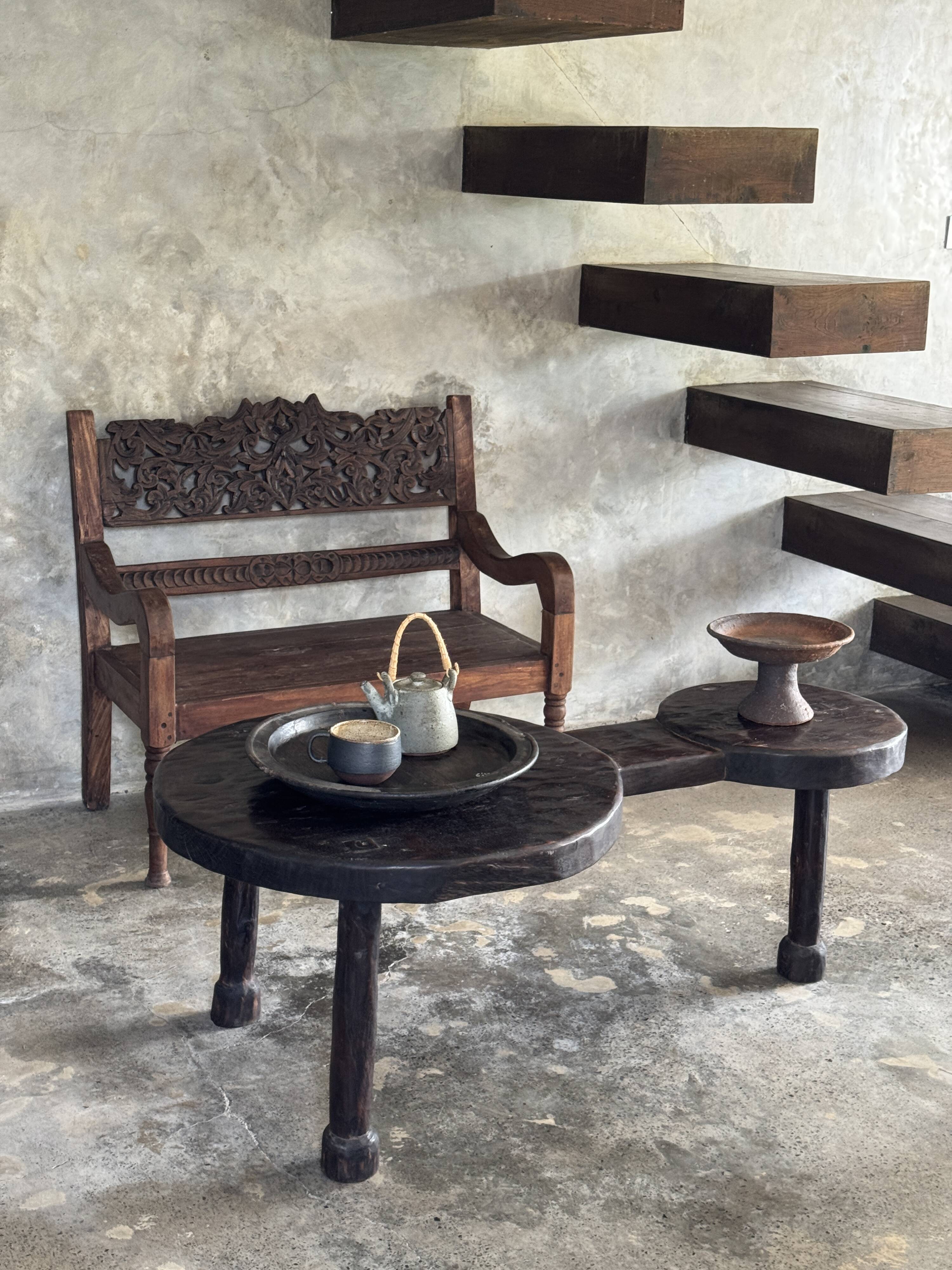 Small antique Indonesian bench in carved teak with plant and floral motifs.