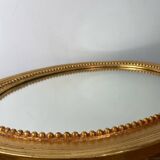 Oval-shaped wooden mirror in gold color