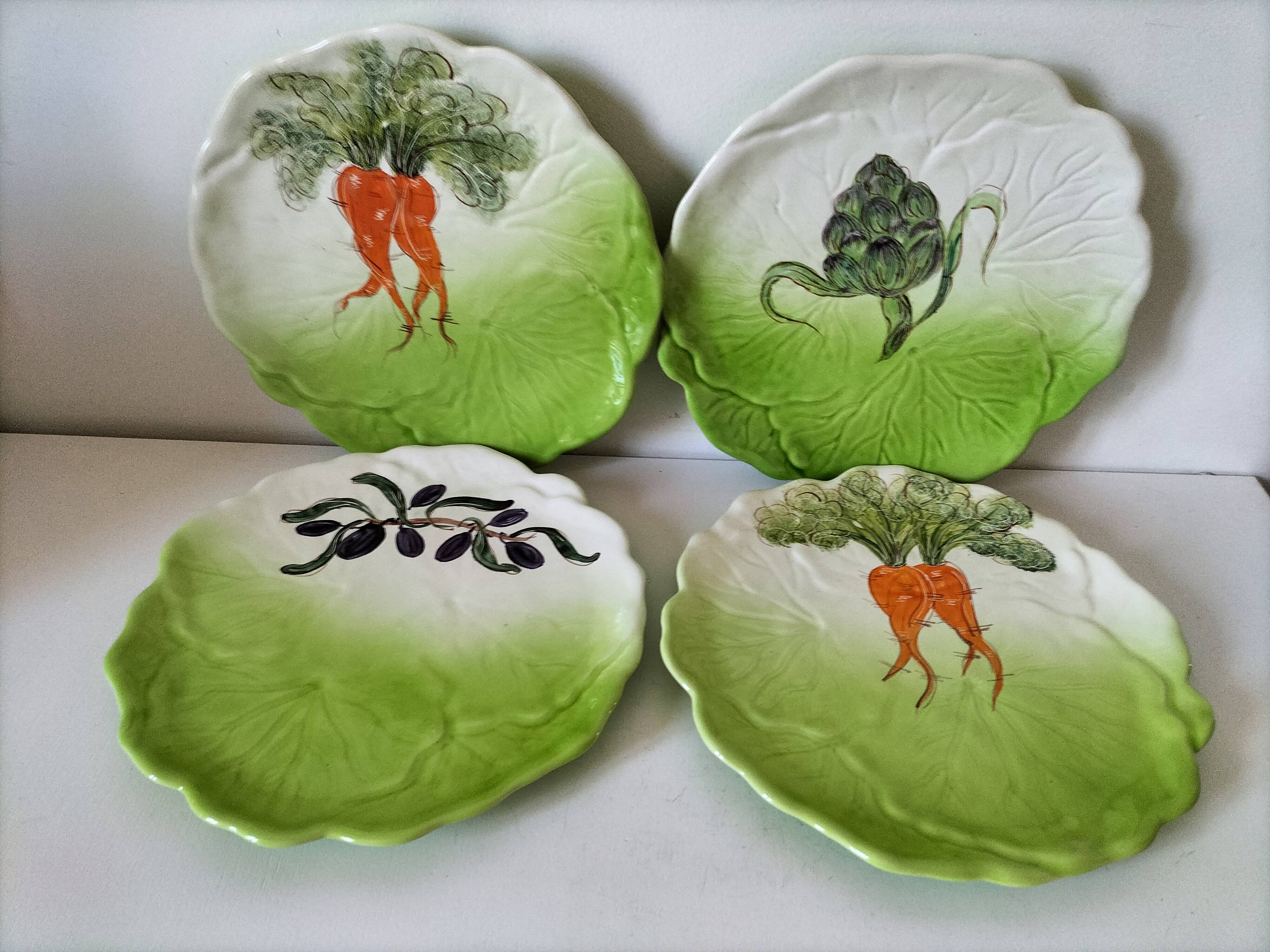 4 hand-decorated earthenware plates with vegetable and green leaf designs.