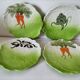 4 hand-decorated earthenware plates with vegetable and green leaf designs.