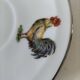Cup and saucer in porcelain decorated with roosters and hens.