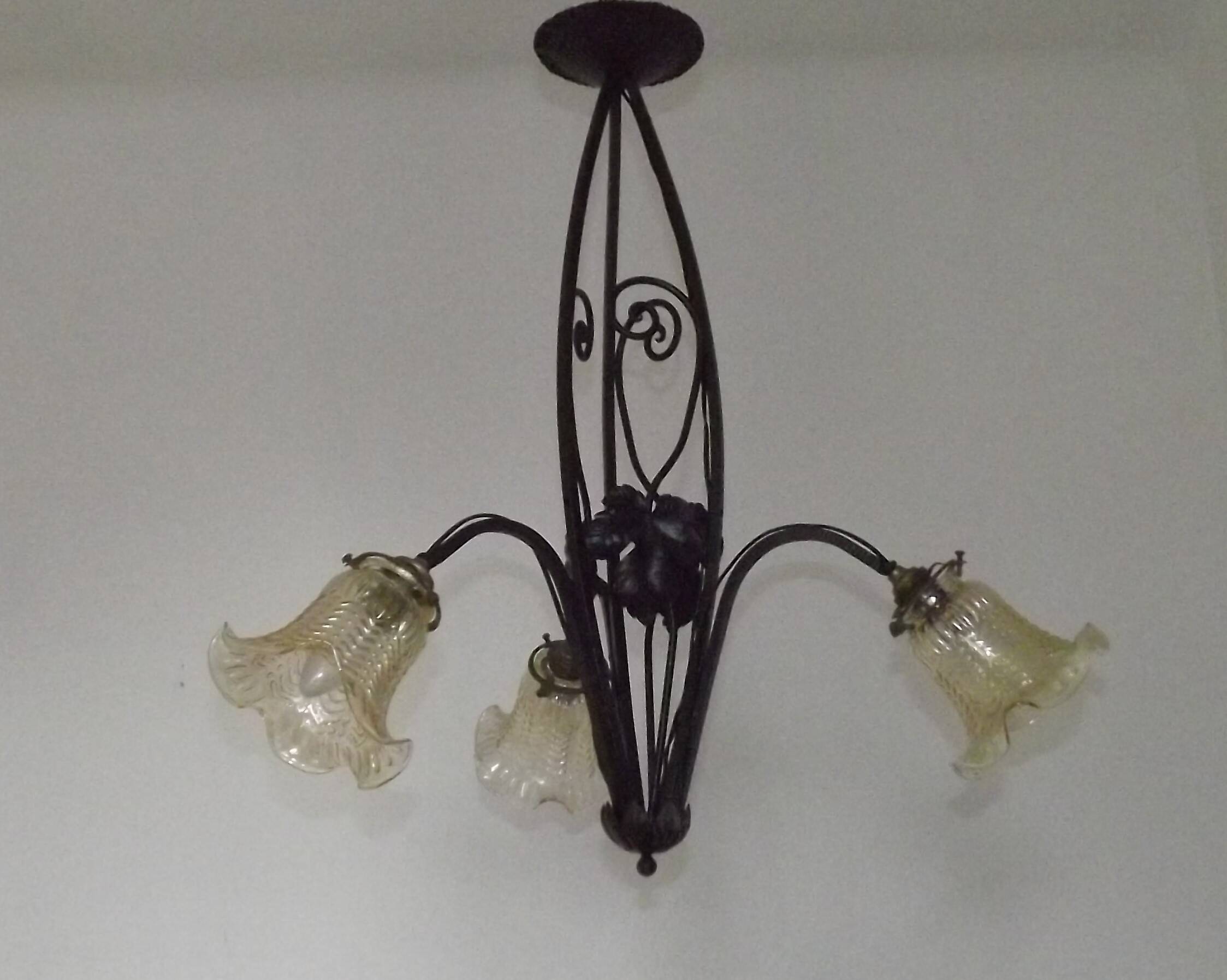 French Art Nouveau leaf detail iron three-light chandelier with amber glass shades.