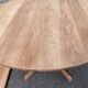 Large extendable round dining table stripped in solid cherry wood with a central leg.