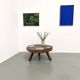 Brutalist coffee table in solid teak, monolithic slab, tripod base.