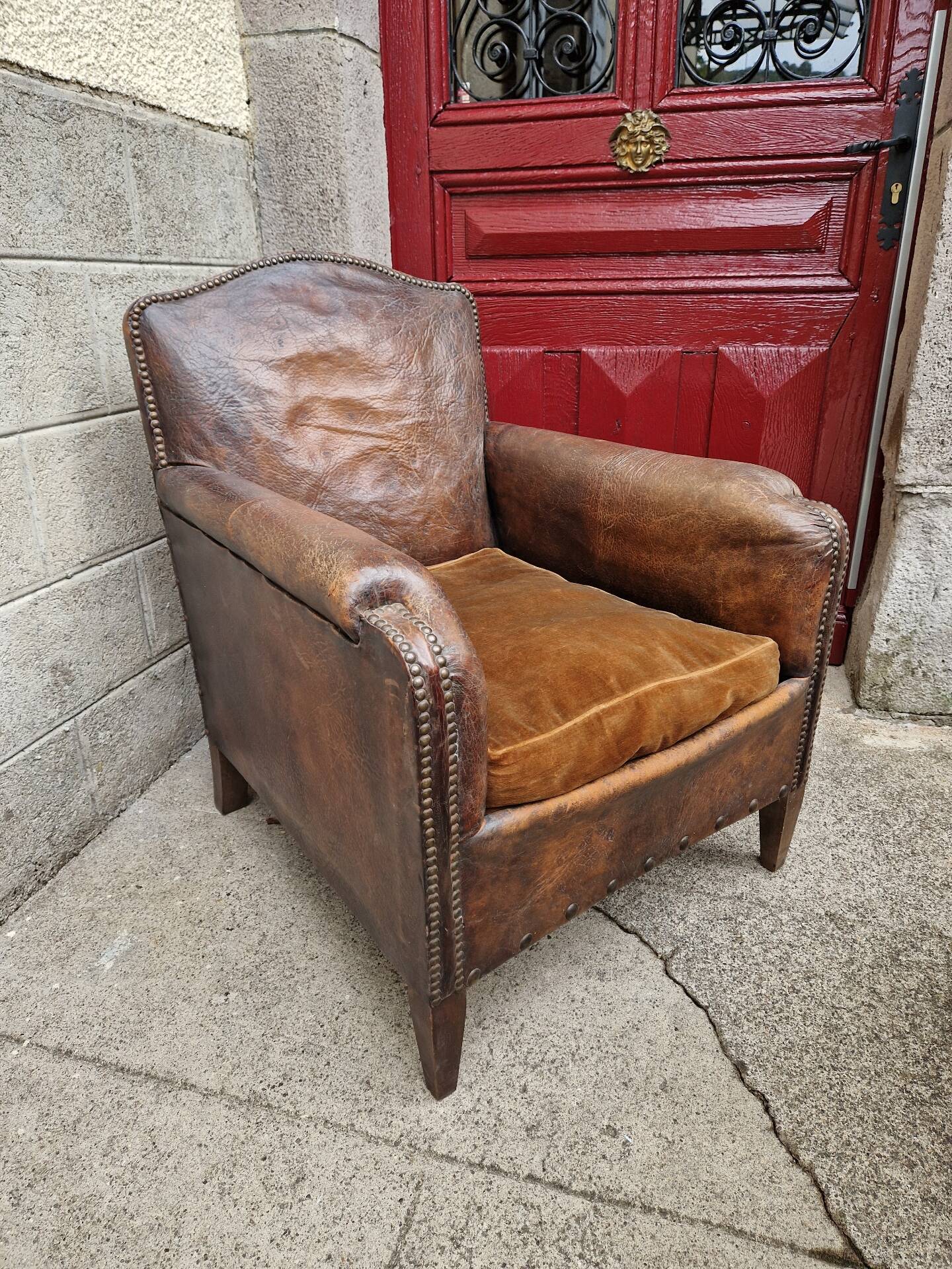 Antique club chair in patinated brown leather, early 20th century English style.