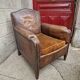 Antique club chair in patinated brown leather, early 20th century English style.