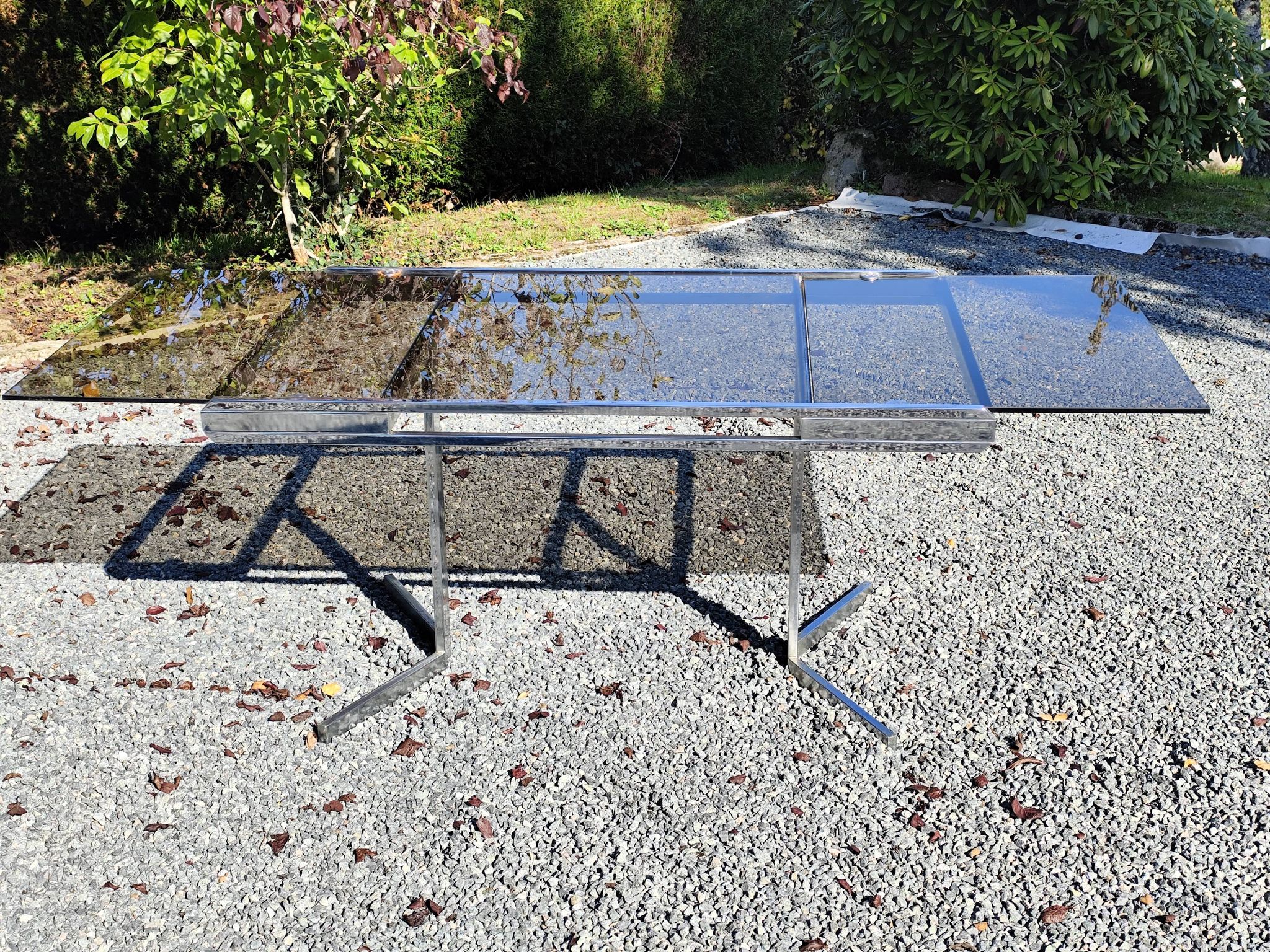 Table pietement chromé et verre fumé année 70 avec allonges