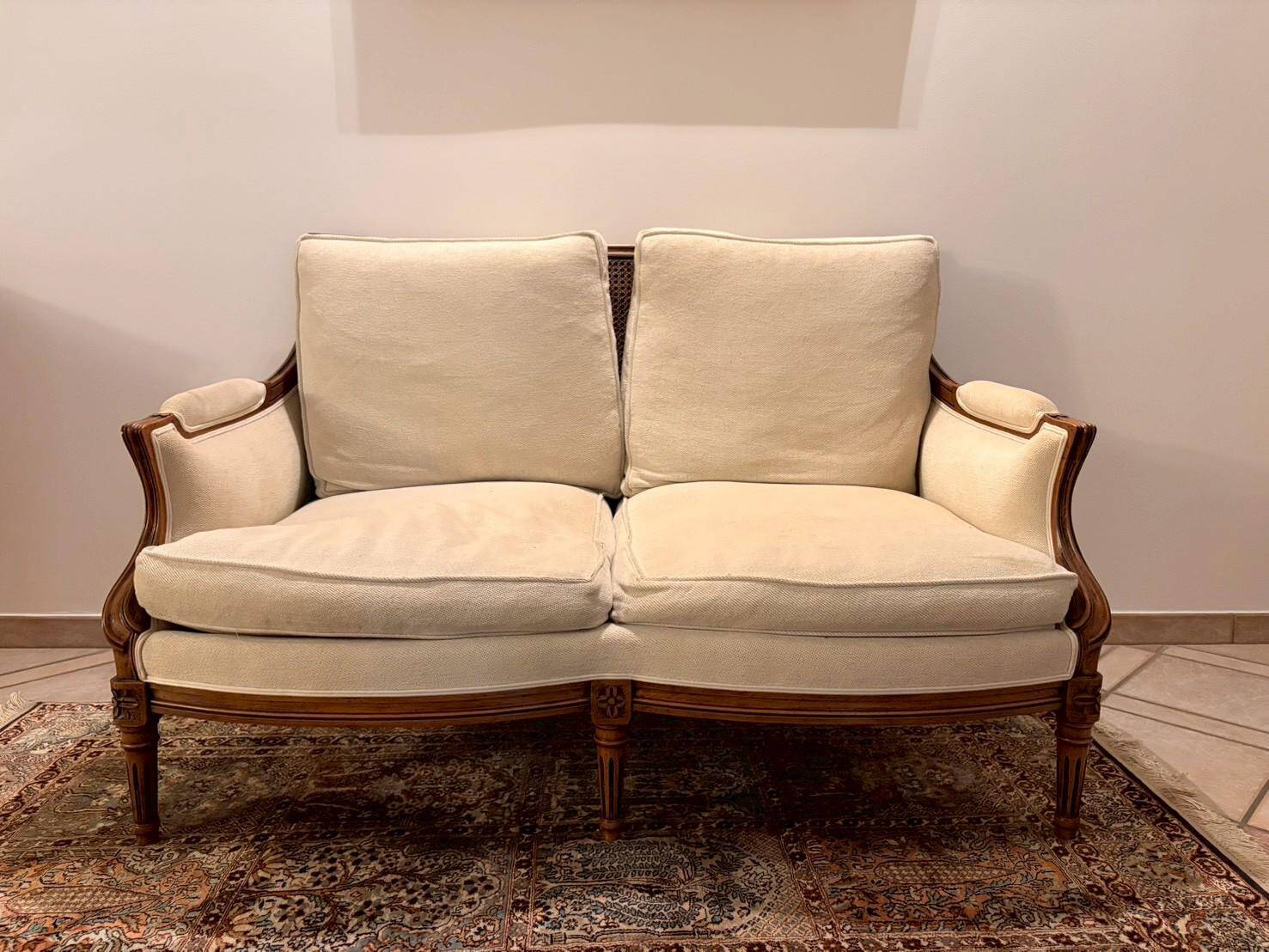 Two-seater canapé by Roche Bobois in Louis XVI style — carved wood, caned sides.