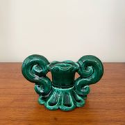 Green ceramic candlestick with curled handles.