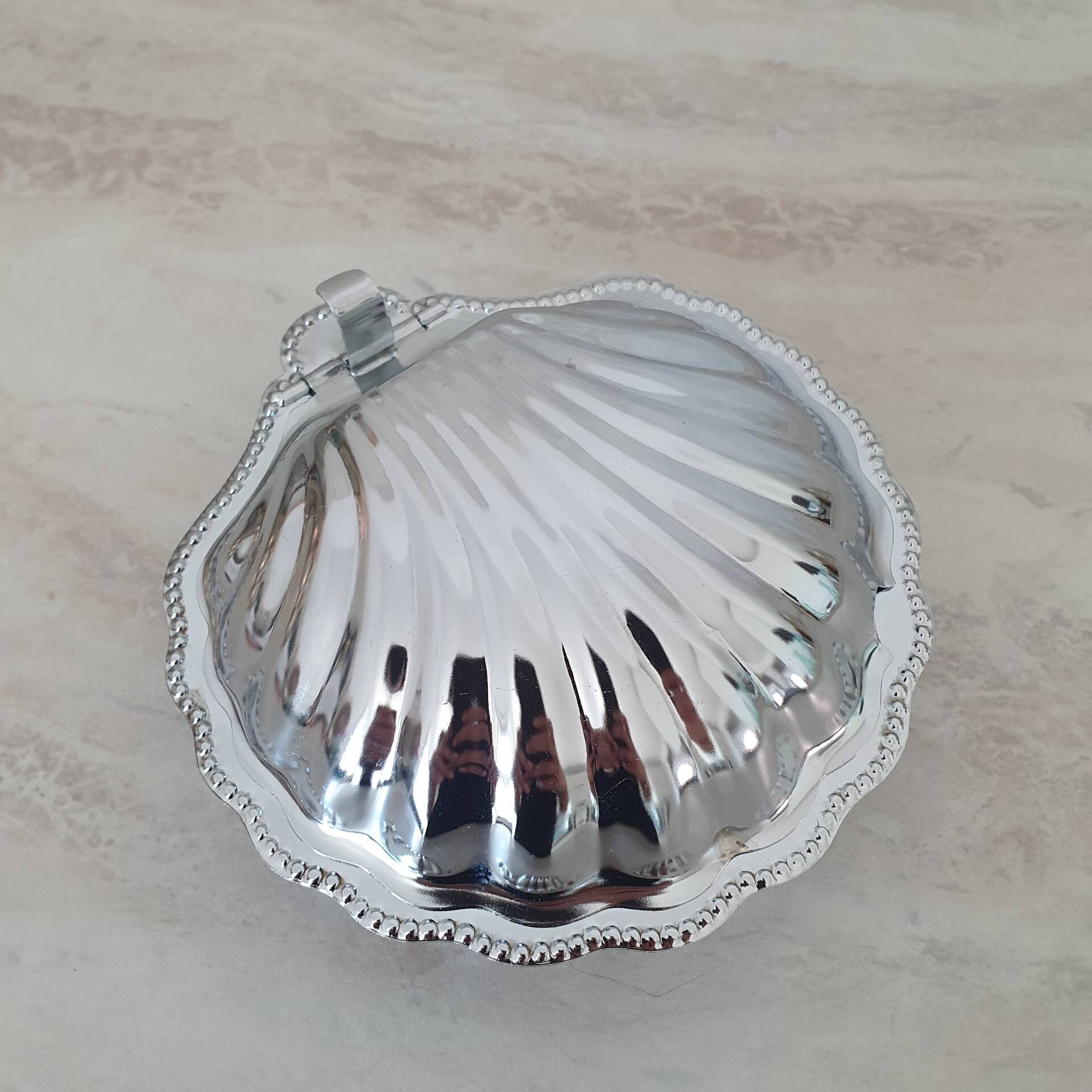Scallop shell butter dish in stainless steel with its white glass saucer.