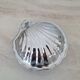 Scallop shell butter dish in stainless steel with its white glass saucer.