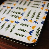 Vintage laminated wooden trivet with yellow, green, and blue flowers