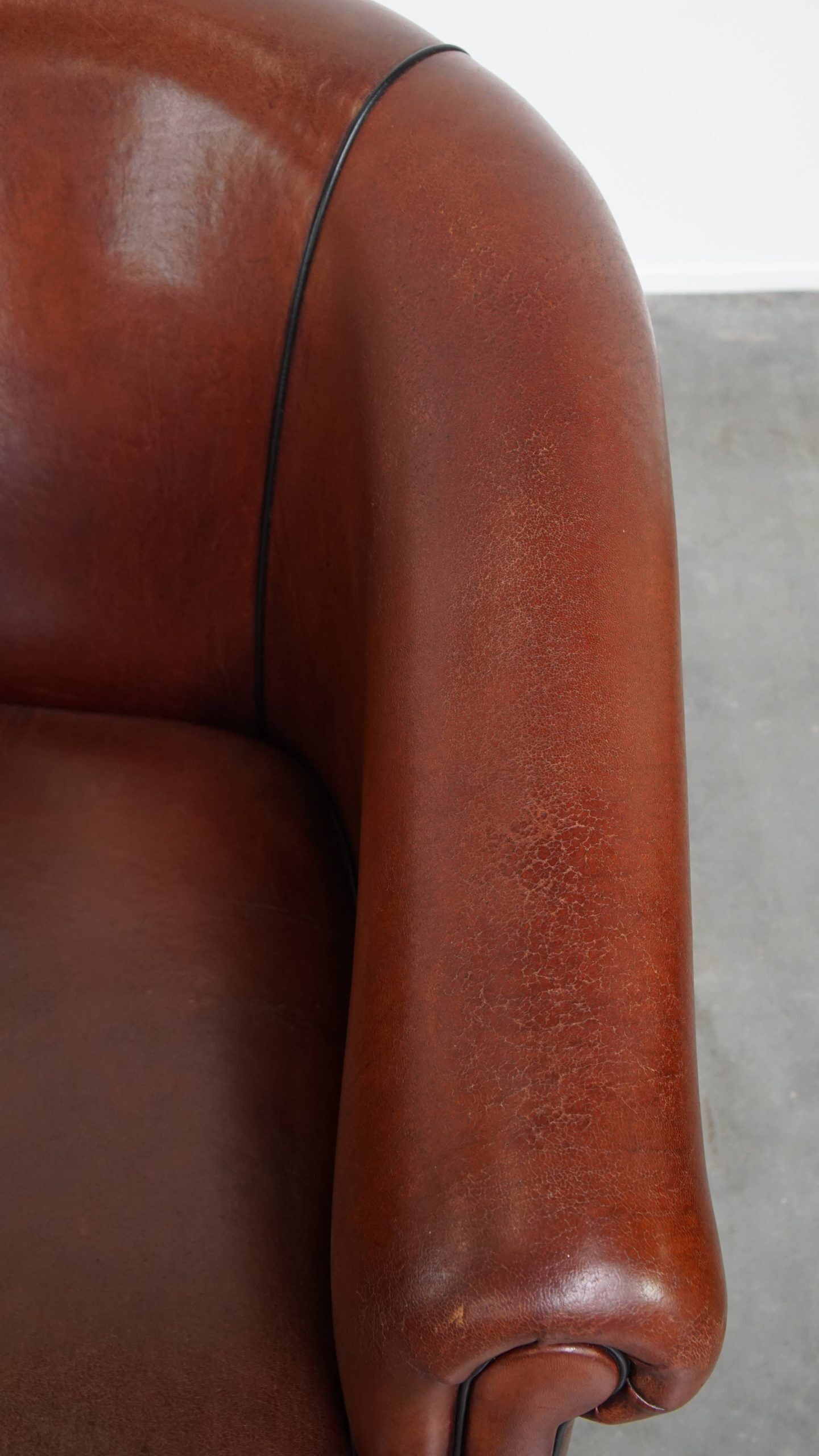 Sheepskin club armchair in a warm deep colour finished with black piping