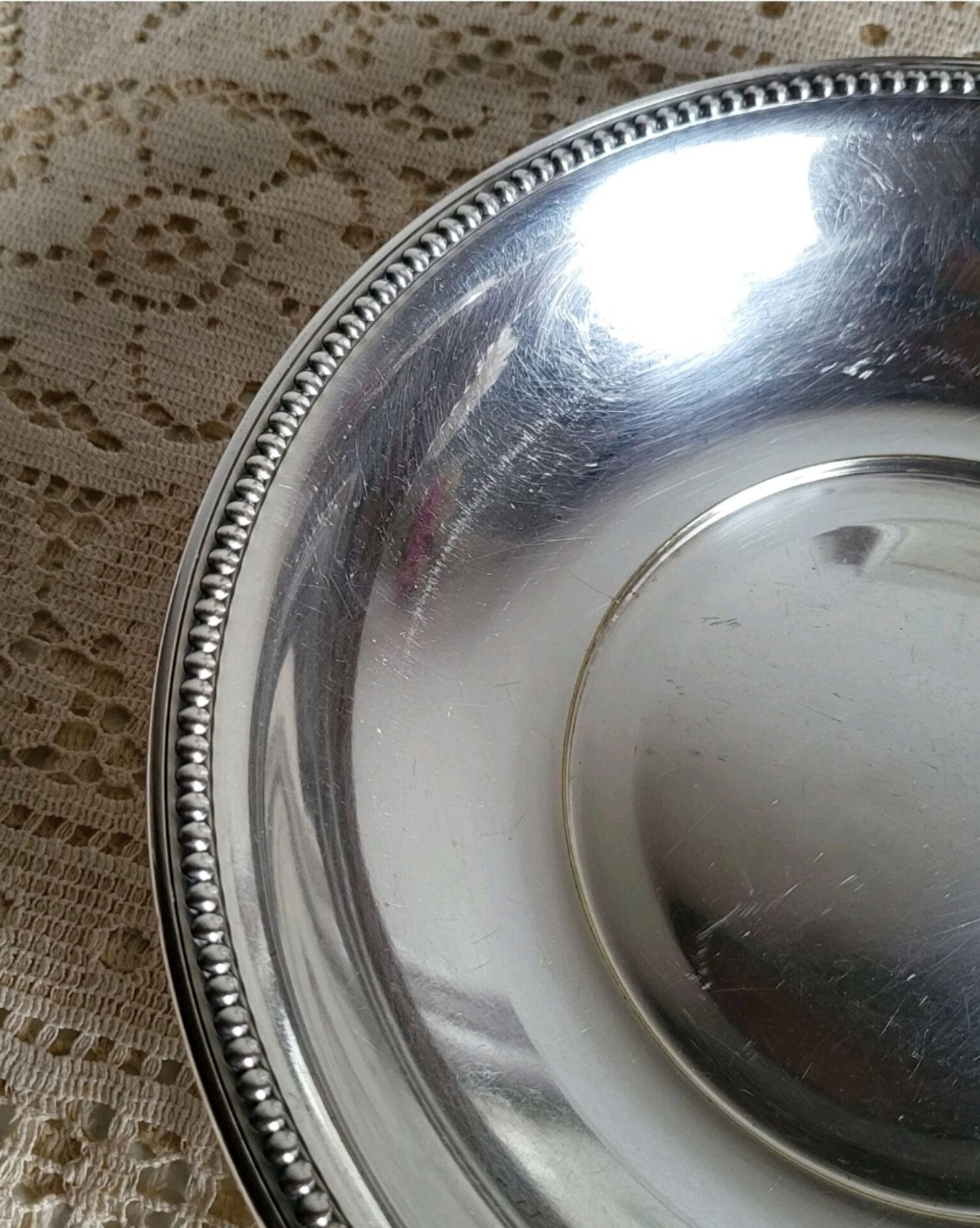 Shallow round metal plate with pearl row decoration.