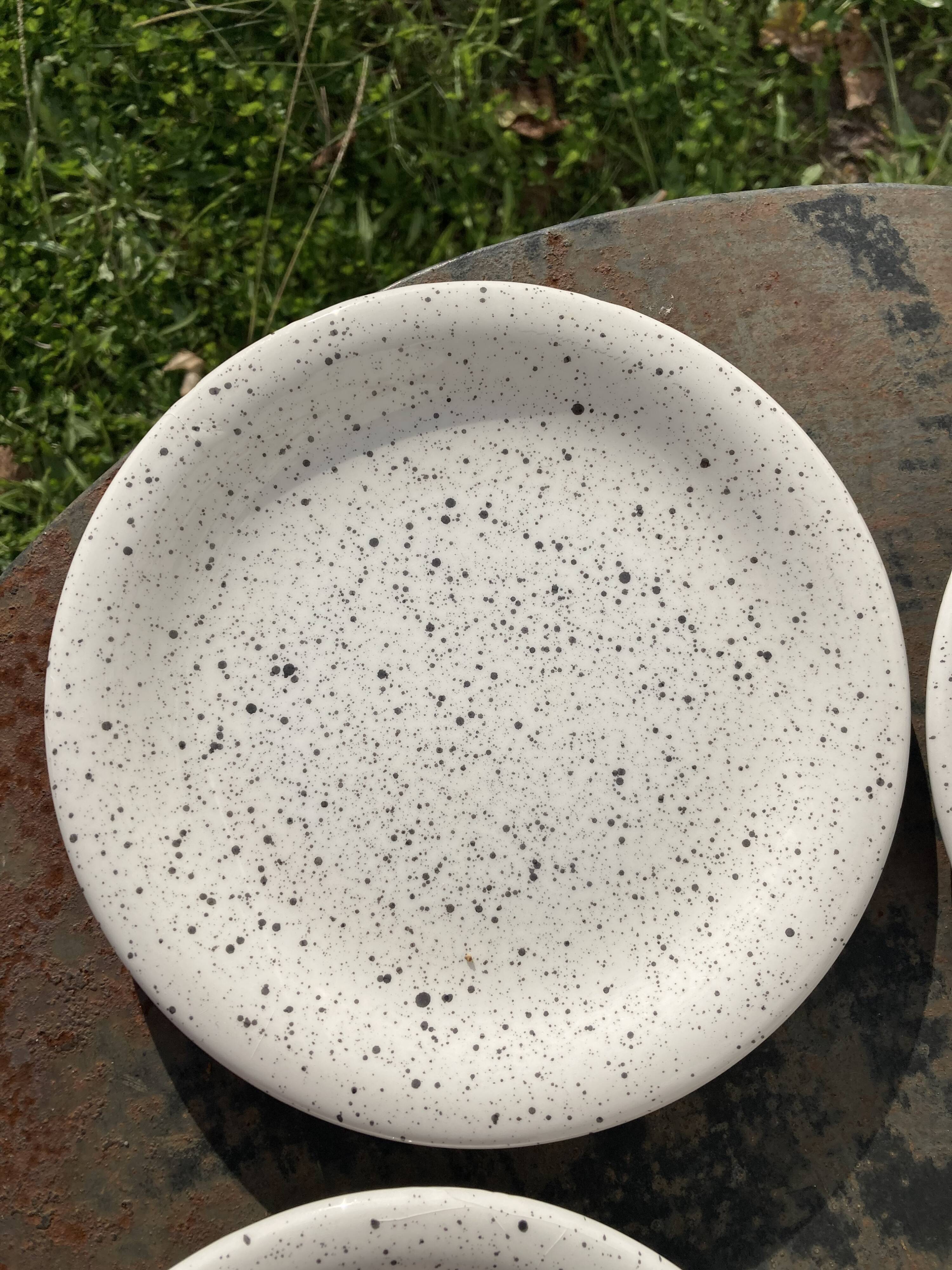 4 black speckled dessert plates on a vintage white background