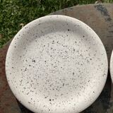 4 black speckled dessert plates on a vintage white background
