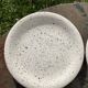 4 black speckled dessert plates on a vintage white background