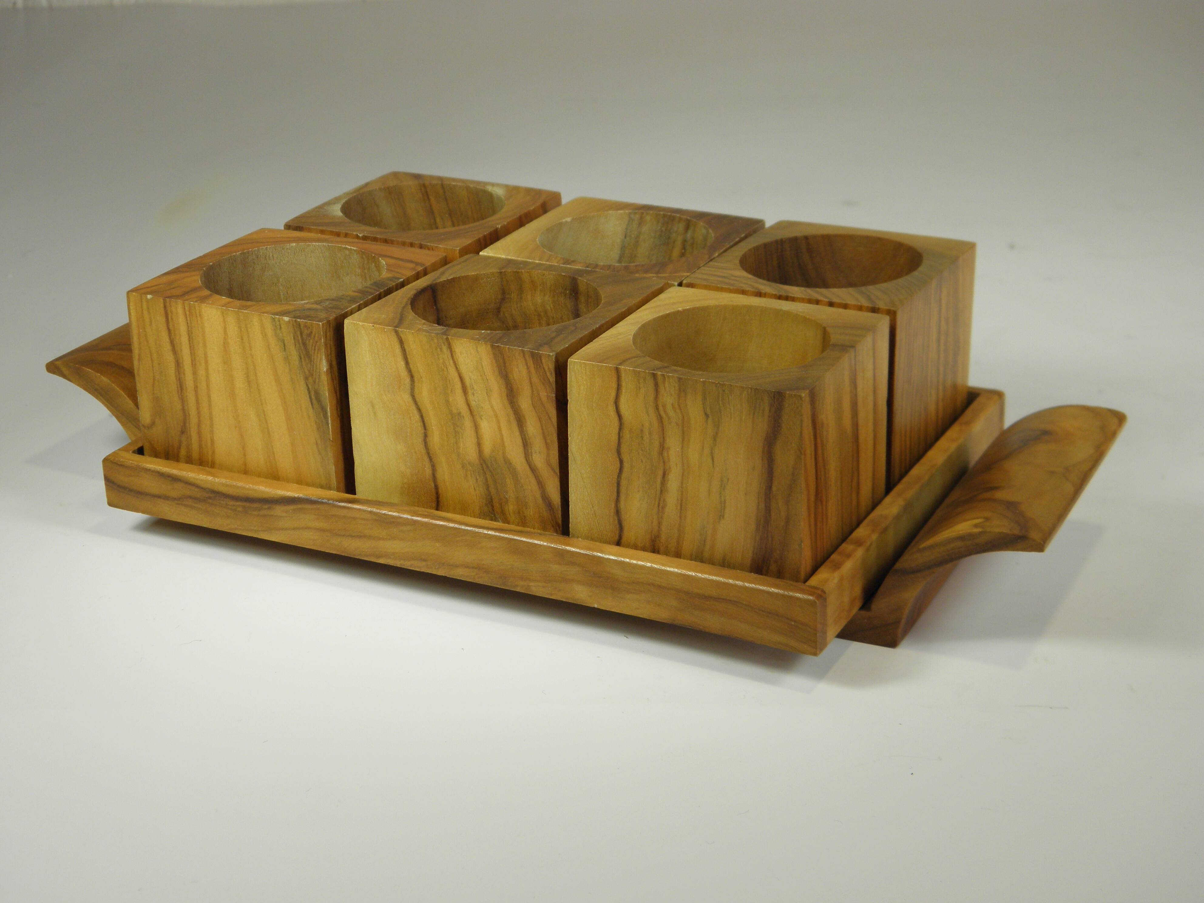Six egg cups on a wooden tray.