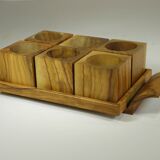Six egg cups on a wooden tray.