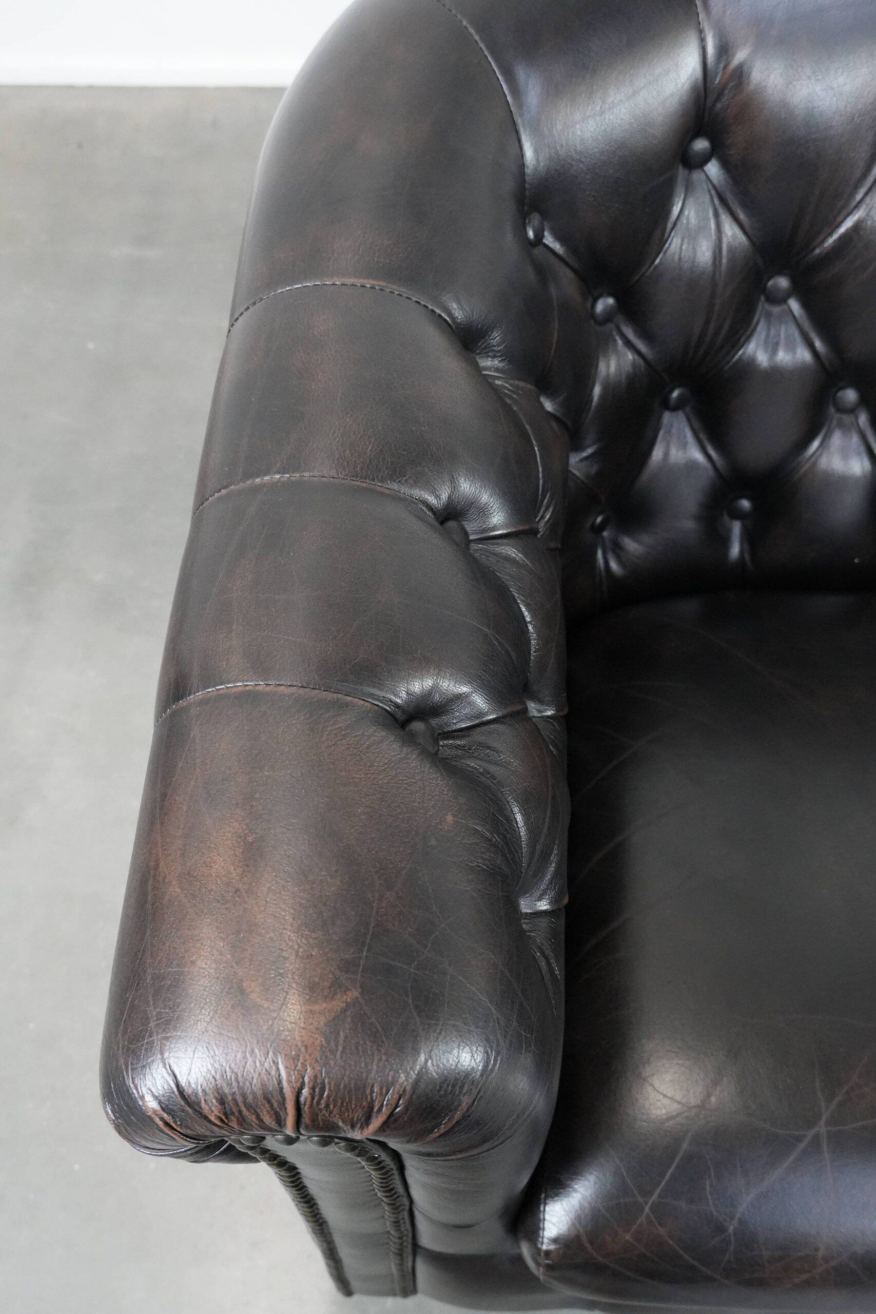 Ensemble de deux luxueux fauteuils club Chesterfield en cuir de vachette noir.