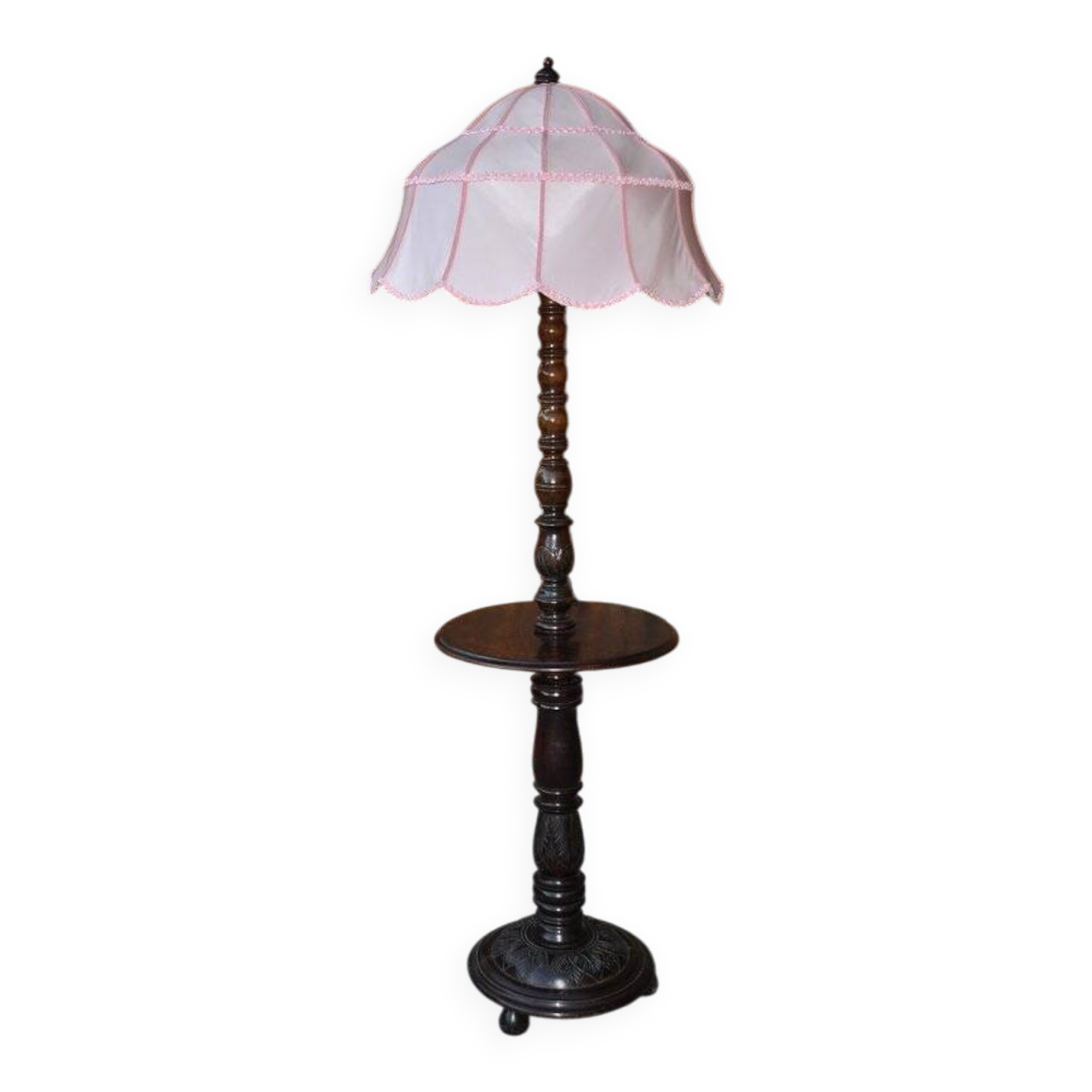 Brown carved wooden floor lamp with a pale pink shade and integrated shelf.