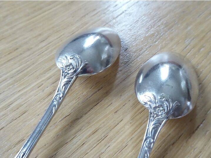 2 small white metal spoons