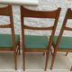 6 modern chairs with banded backs and green faux leather seats.