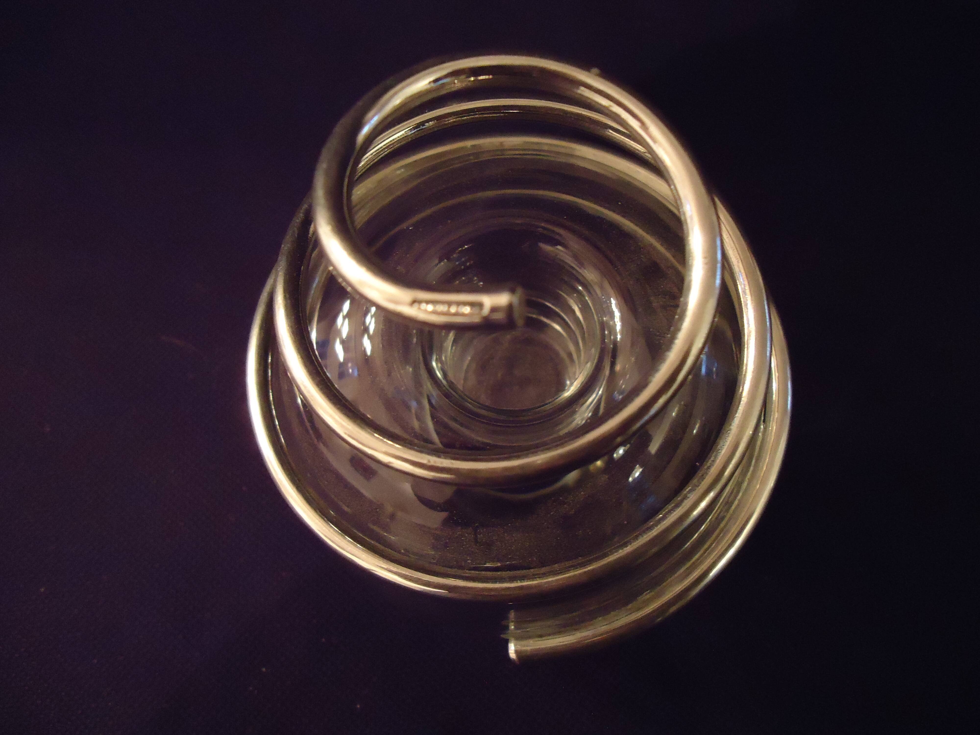 Round glass candle holder with silver-plated metal spiral.