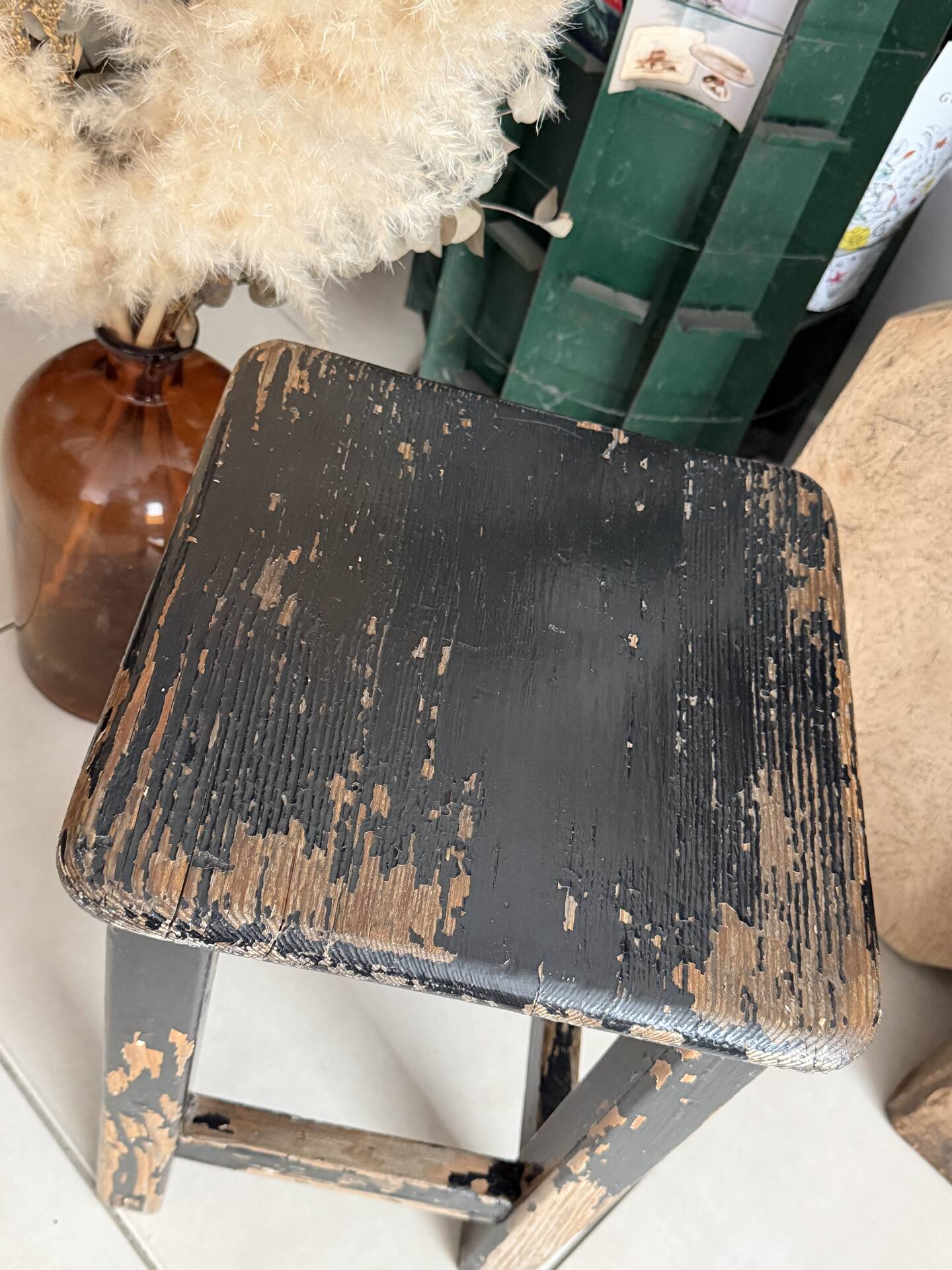 Solid wood stool with a worn black patina.