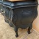 Curved commode painted in black and wood.