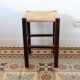 Vintage rustic stool in wood with a straw seat.