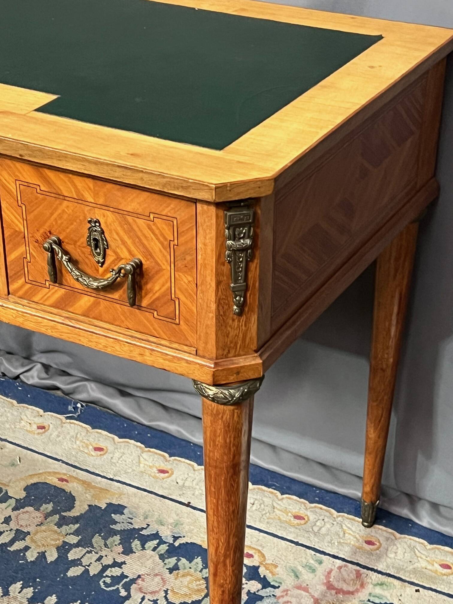 Louis XVI style marquetry desk. The top is decorated with green leather.
