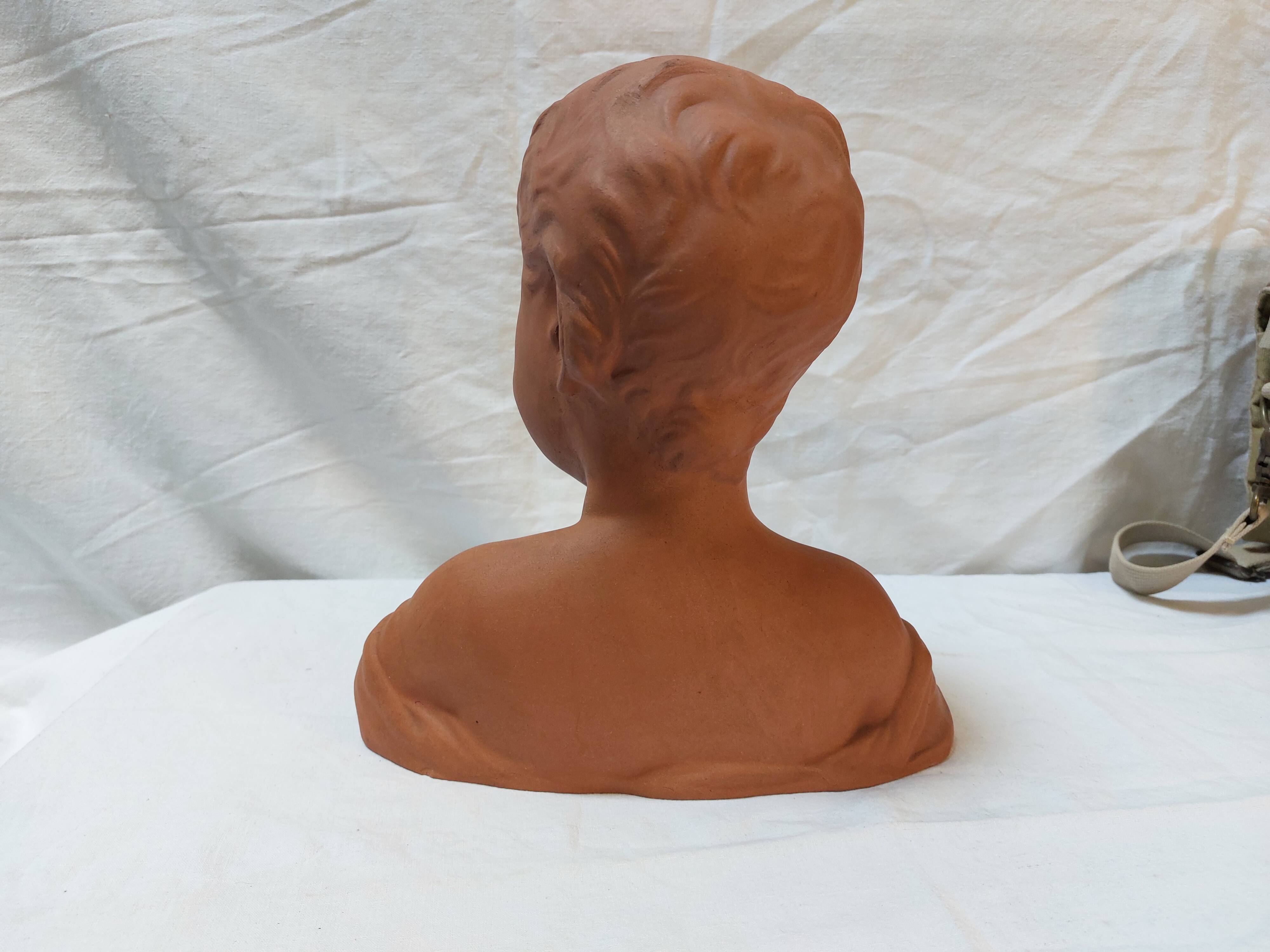 Terracotta bust of a smiling little boy.