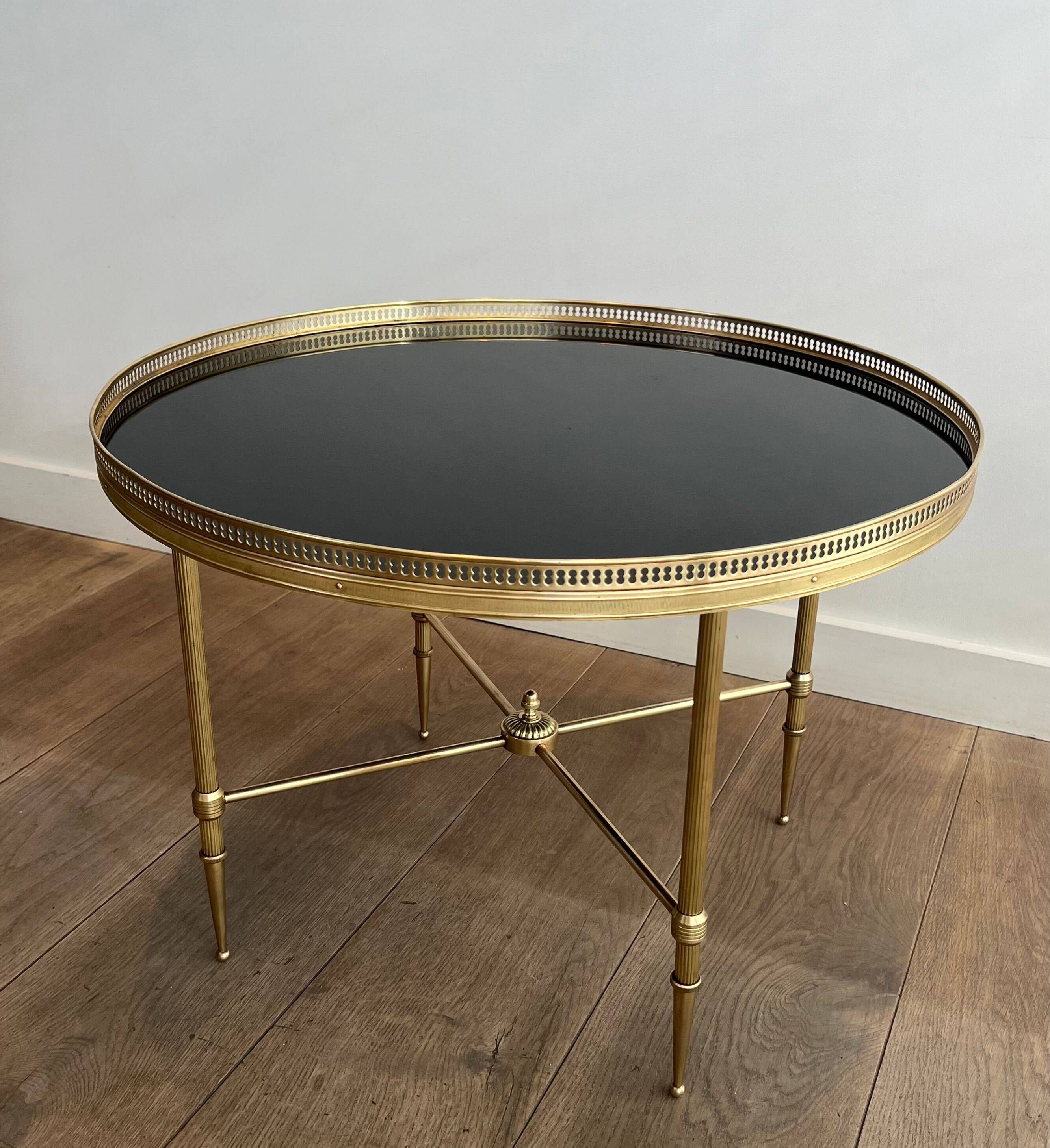 Round coffee table in brass with a black lacquered glass top from Maison Jansen.