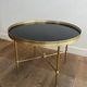 Round coffee table in brass with a black lacquered glass top from Maison Jansen.