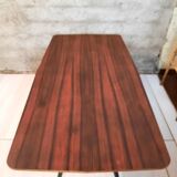 Table à manger en bois de teck et pieds en métal peint.
