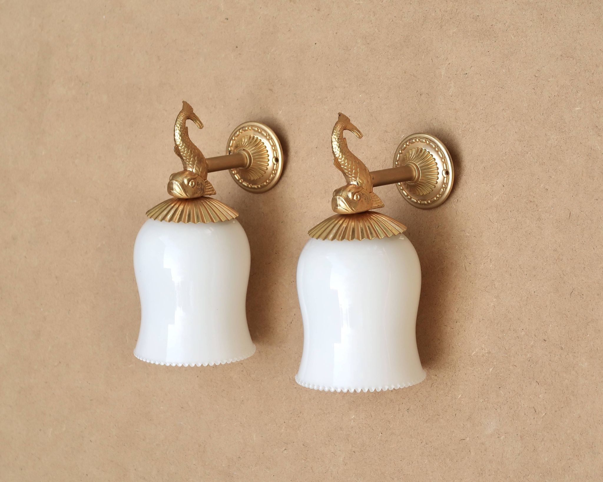 Pair of gold metal and opaque glass wall lights adorned with fish from the 1950s.