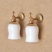 Pair of gold metal and opaque glass wall lights adorned with fish from the 1950s.