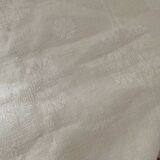 Damask tablecloth with a floral pattern and a central embroidered monogram.