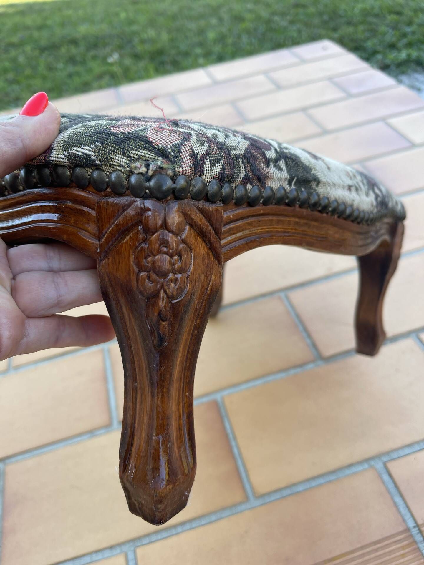 Antique wooden footstool with hand-carved details and floral upholstery –