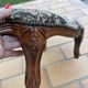 Antique wooden footstool with hand-carved details and floral upholstery –