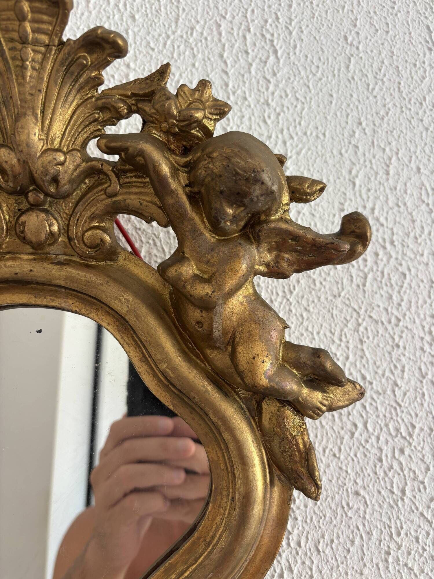 Antique rococo mirror with putti, gilded carved wood and stucco frame, 19th century.