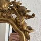 Antique rococo mirror with putti, gilded carved wood and stucco frame, 19th century.