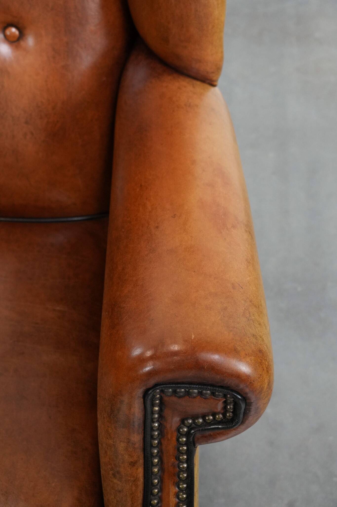 Large sheepskin wingback chair with black piping and decorative nails