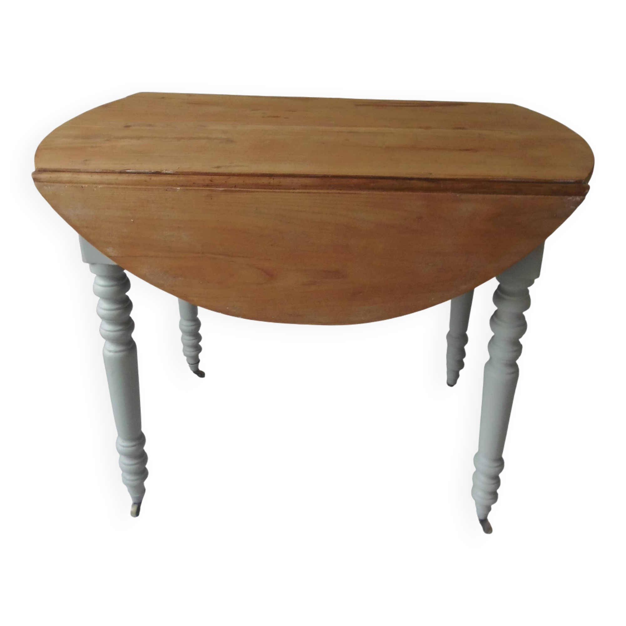 Raised walnut table with drop-leaf top, base on verdigris castors.