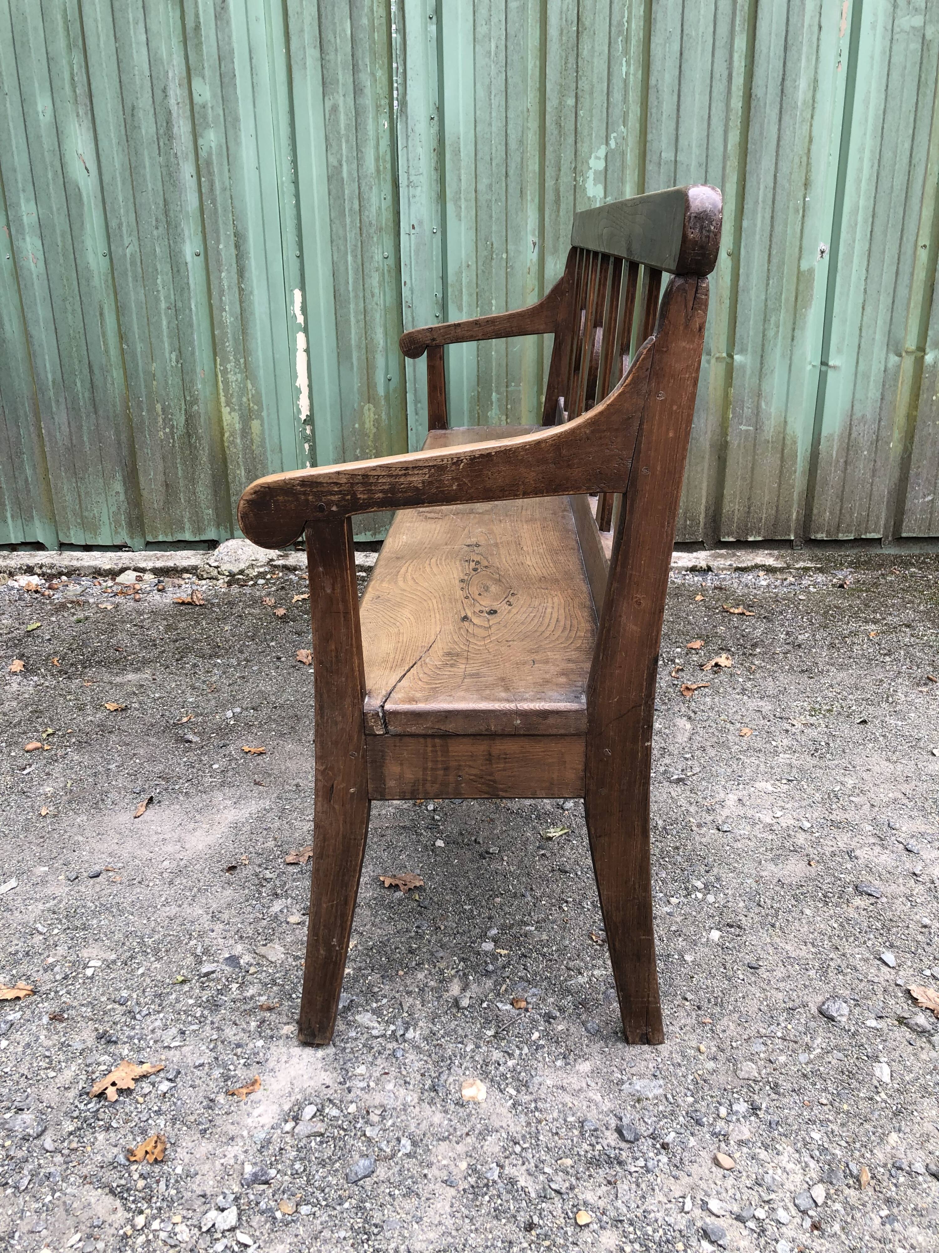 Duo of old solid oak benches with backs and armrests.