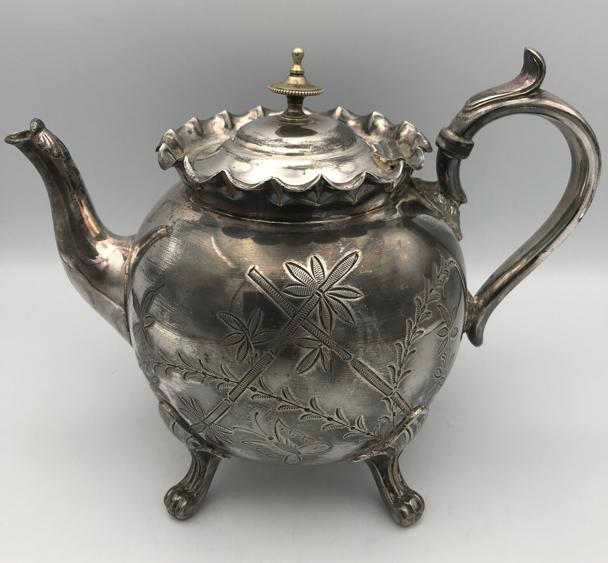 Old teapot pourer in silver metal decorated with foliage and butterflies
