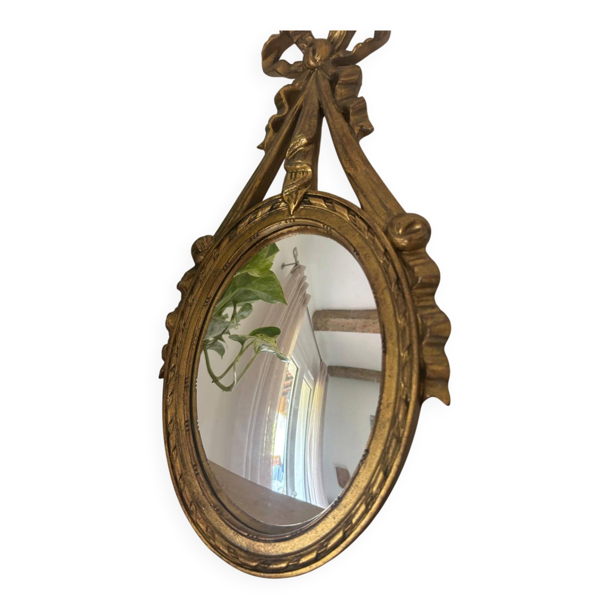 Oval convex witch mirror with golden ribbon mouldings.