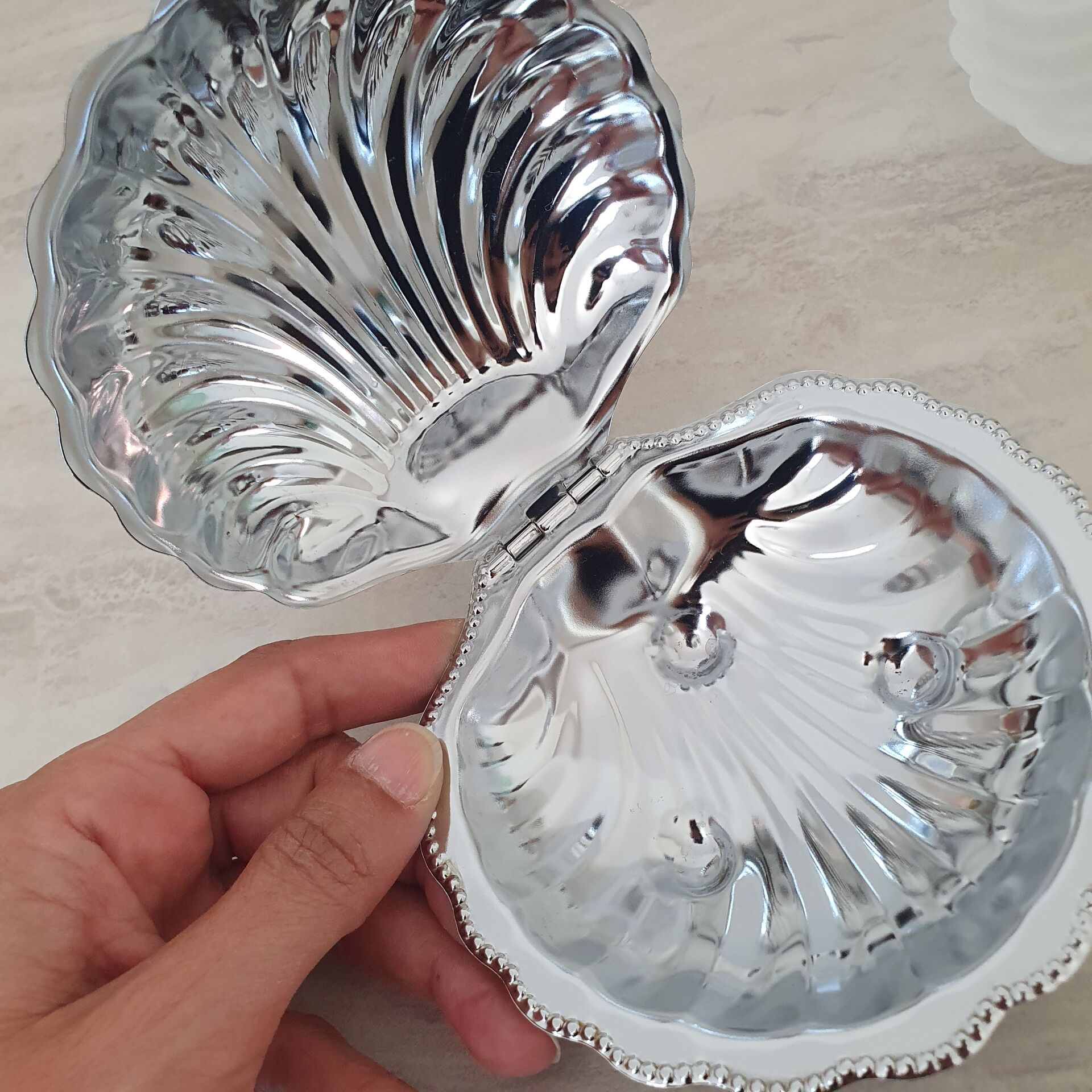 Scallop shell butter dish in stainless steel with its white glass saucer.